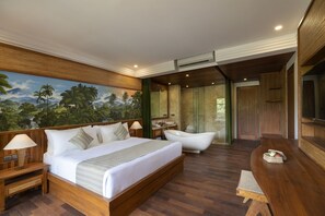 Une chambre spacieuse avec un grand lit, une baignoire, un bureau en bois et une fresque représentant un paysage tropical.