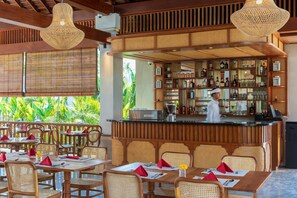 Un restaurant doté de meubles en bois, d’un bar et offrant une vue sur la verdure environnante.