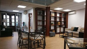 Un salon spacieux doté d’un plancher en bois, d’une table basse en verre, d’un canapé et d’un coin repas avec des chaises.