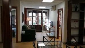Un vaste espace de vie comprenant un canapé, une table basse en verre et une bibliothèque.