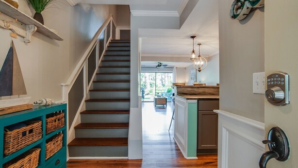 Un escalier menant à une cuisine dotée d’un plancher en bois, d’un meuble de rangement de couleur turquoise et d’un luminaire suspendu.