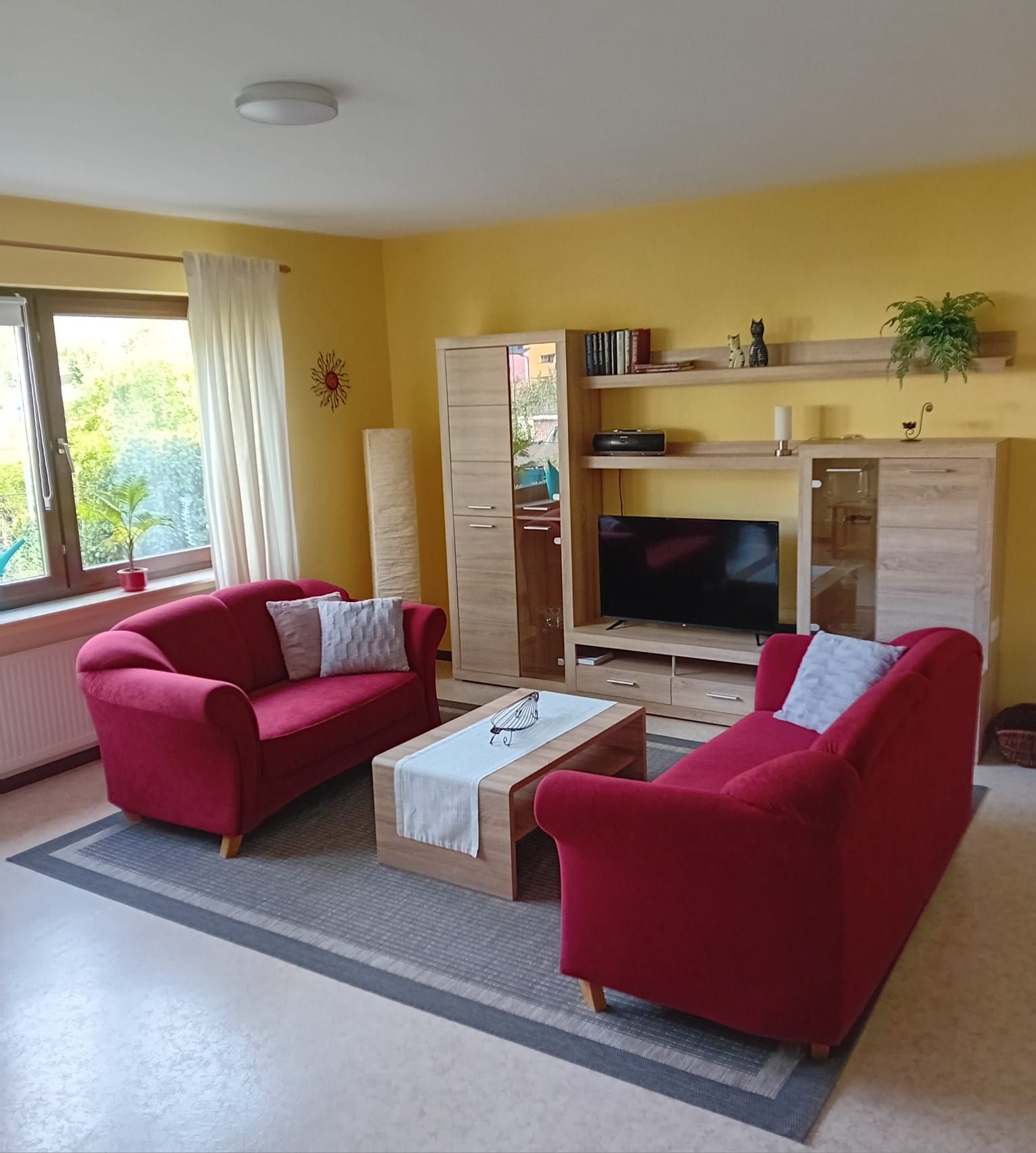 Ein Wohnzimmer mit zwei roten Sofas, einem Couchtisch, einem Fernseher und einem Kamin.