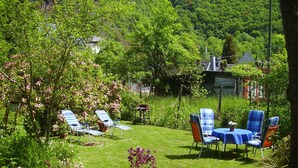 Un jardin agrémenté d’une table et de chaises, entouré d’une végétation luxuriante et de plantes en fleurs.