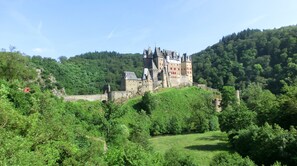 Un château entouré d’une végétation luxuriante et de collines.