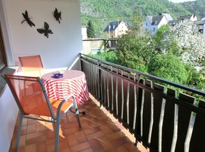 Un balcon avec une table et des chaises, une vue sur un village et des éléments décoratifs sur les murs.