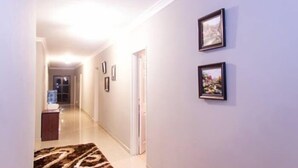 A hallway with framed pictures on the wall, a carpet, and a door at the end. - Sarum Lodge (Harare)