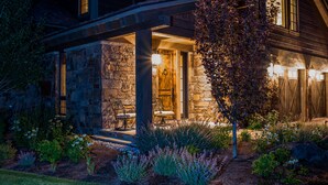 A stone house with a covered porch, a wooden door, and a bench. - Bunchberry Court Luxury Home at Tributary in Driggs, Idaho with Amazing Views (Driggs)