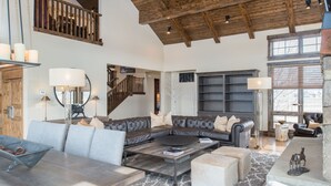 A spacious living room with a high wooden ceiling, a large leather sofa, a coffee table, and a fireplace. - Bunchberry Court Luxury Home at Tributary in Driggs, Idaho with Amazing Views (Driggs)