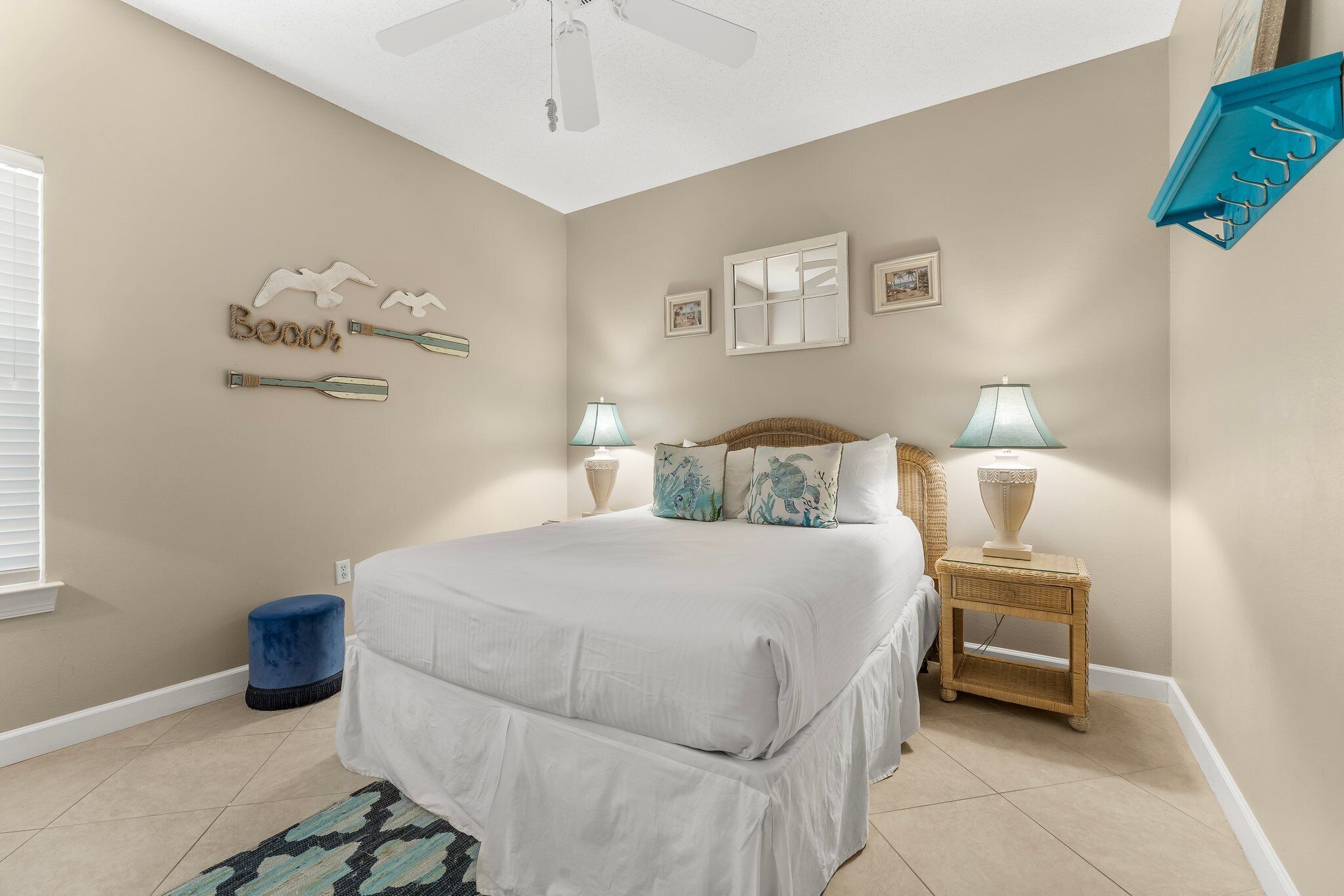 A bedroom with a bed, two nightstands, a ceiling fan, and wall decorations.
