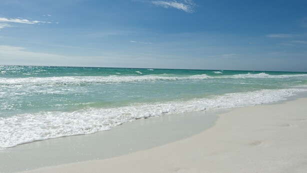 Ein Strand mit klarem türkisblauem Wasser und weißem Sand.
