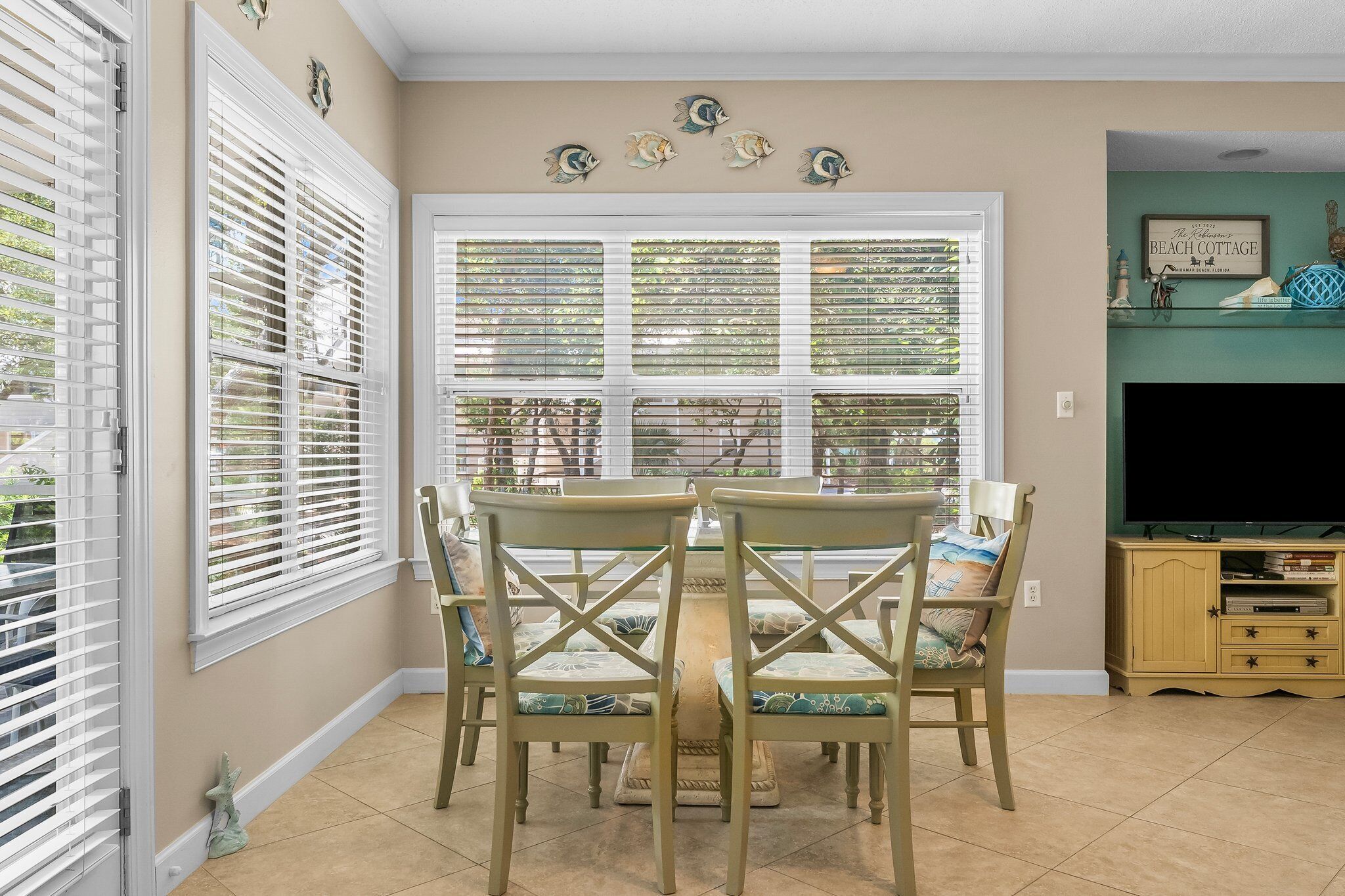 A dining area with a table and chairs, a television, and decorative wall art.