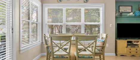 A dining area with a table and chairs, a television, and decorative wall art.