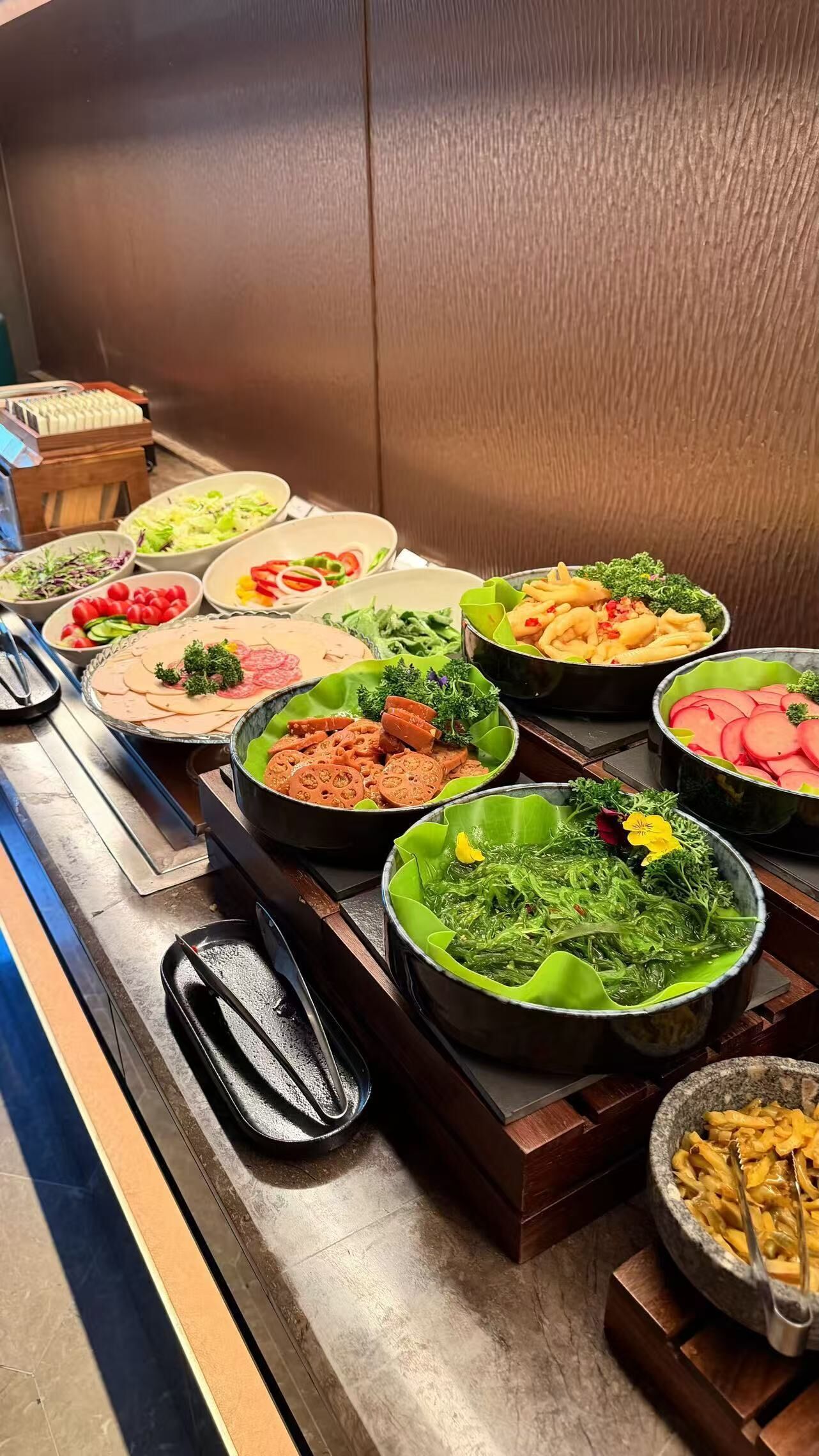 Un bufé con diversos platos, incluyendo ensaladas, carnes y pastas.