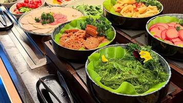 Un bufé con diversos platos, incluyendo ensaladas, carnes y pastas.