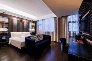 A modern hotel room with a large bed, a dark-colored sofa, a small table, and a TV. - Crystal Shanghai North Bund (Shanghai)
