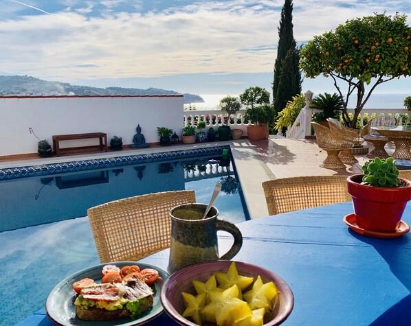 Ein Tisch am Pool mit Essen, Obst und einem Getränk.