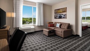A hotel room with a sofa, a TV, a desk, and a window with curtains. - TownePlace Suites by Marriott Memphis Olive Branch (Olive Branch)