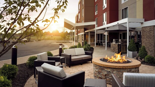 A hotel patio with outdoor seating, a fire pit, and a view of the building's entrance. - TownePlace Suites by Marriott Memphis Olive Branch (Olive Branch)