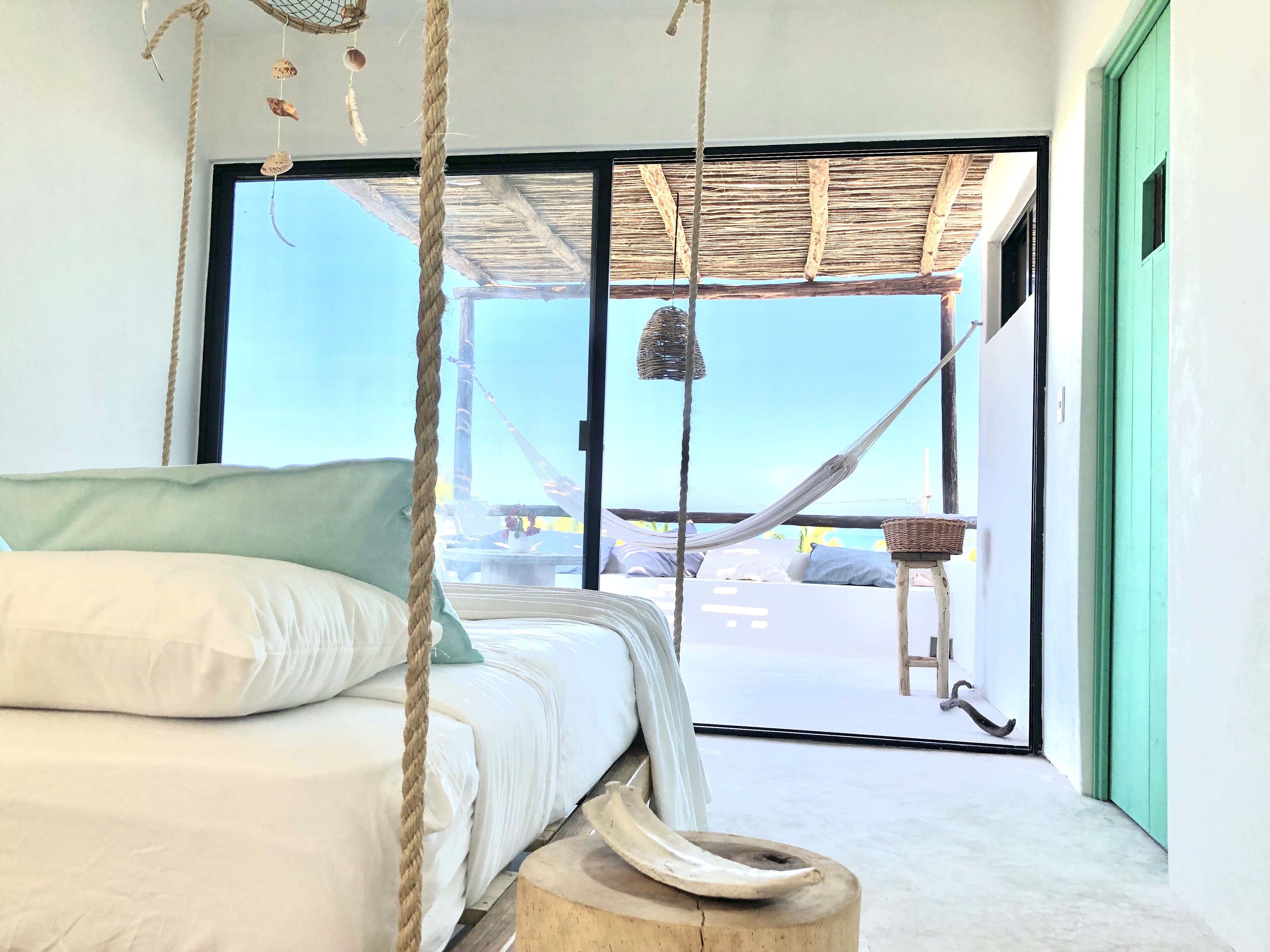A bedroom with a bed, a hammock, and a view of the beach.