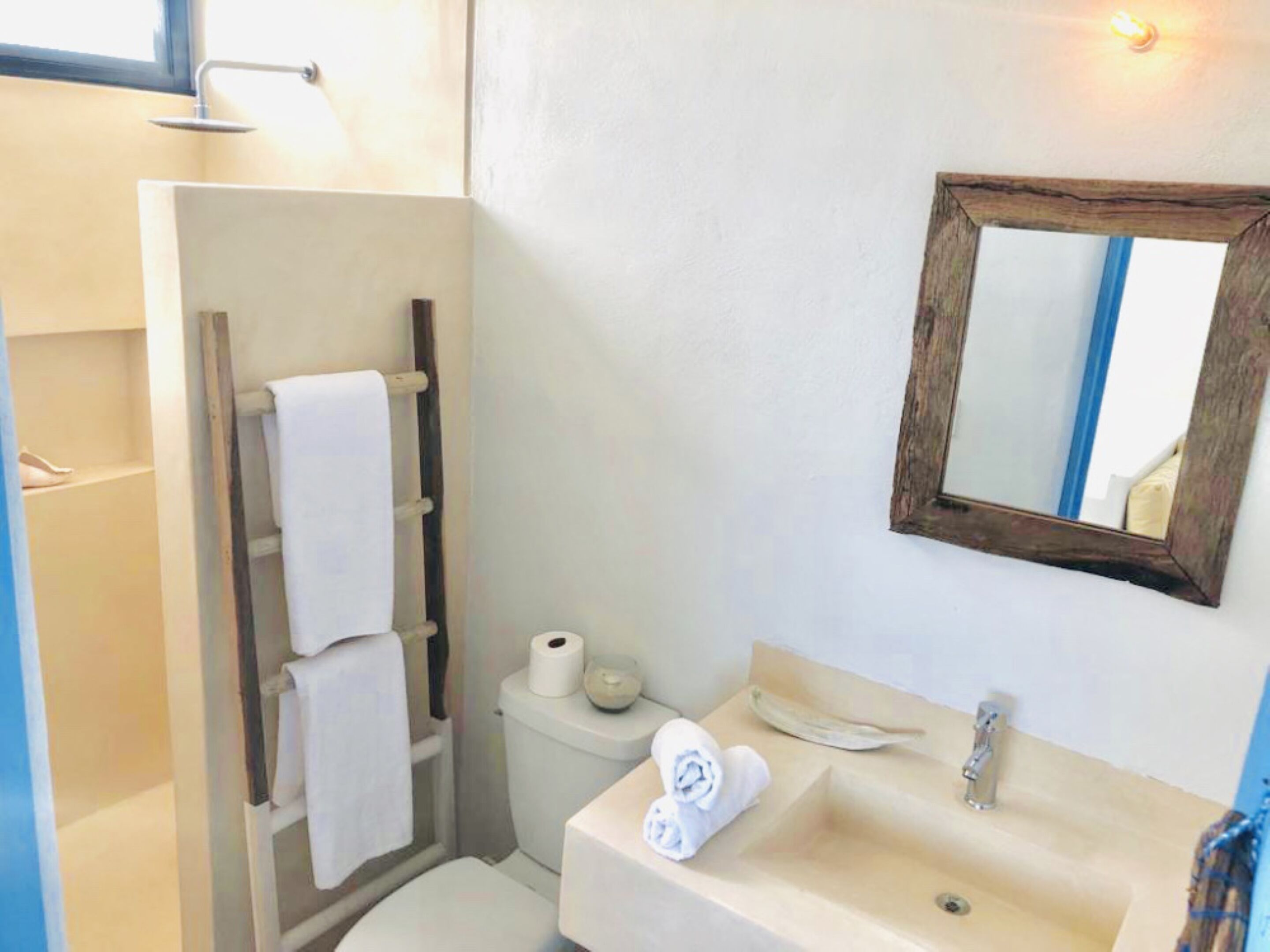 A bathroom with a shower, toilet, sink, and a mirror.