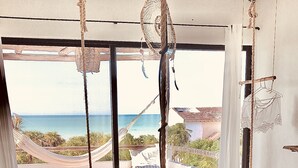Un dormitorio con cama, una silla colgante y vista al océano.