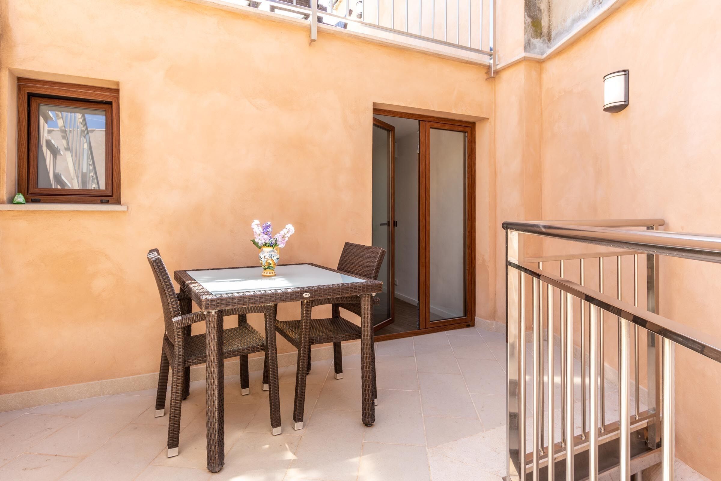 A balcony with a table and chairs, a sliding glass door, and a small window.