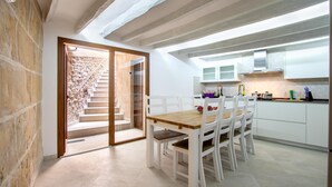 Eine moderne Küche mit weißen Schränken, einem Holztisch und einer Treppe, die zu einem Erker führt.