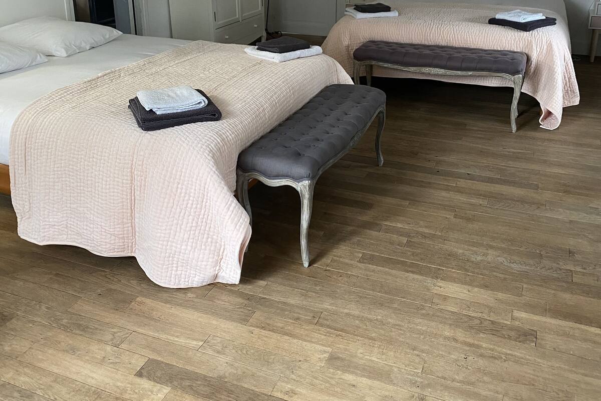 A bedroom with two beds, a bench, and a wardrobe.
