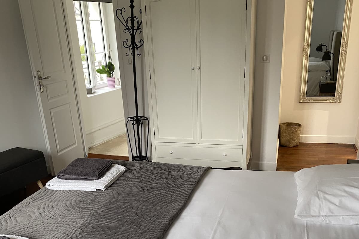 A bedroom with a bed, a wardrobe, and a mirror.