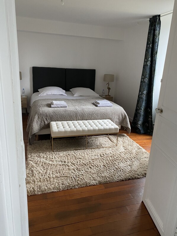 Une chambre à coucher avec un lit, des tables de chevet, une lampe, un banc et un tapis moelleux.