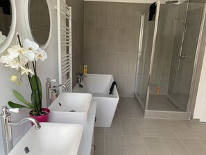 Une salle de bain moderne avec deux lavabos, une baignoire, une douche et un miroir.