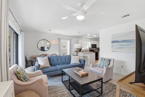 A modern living room with a sofa, chairs, a coffee table, and a television.