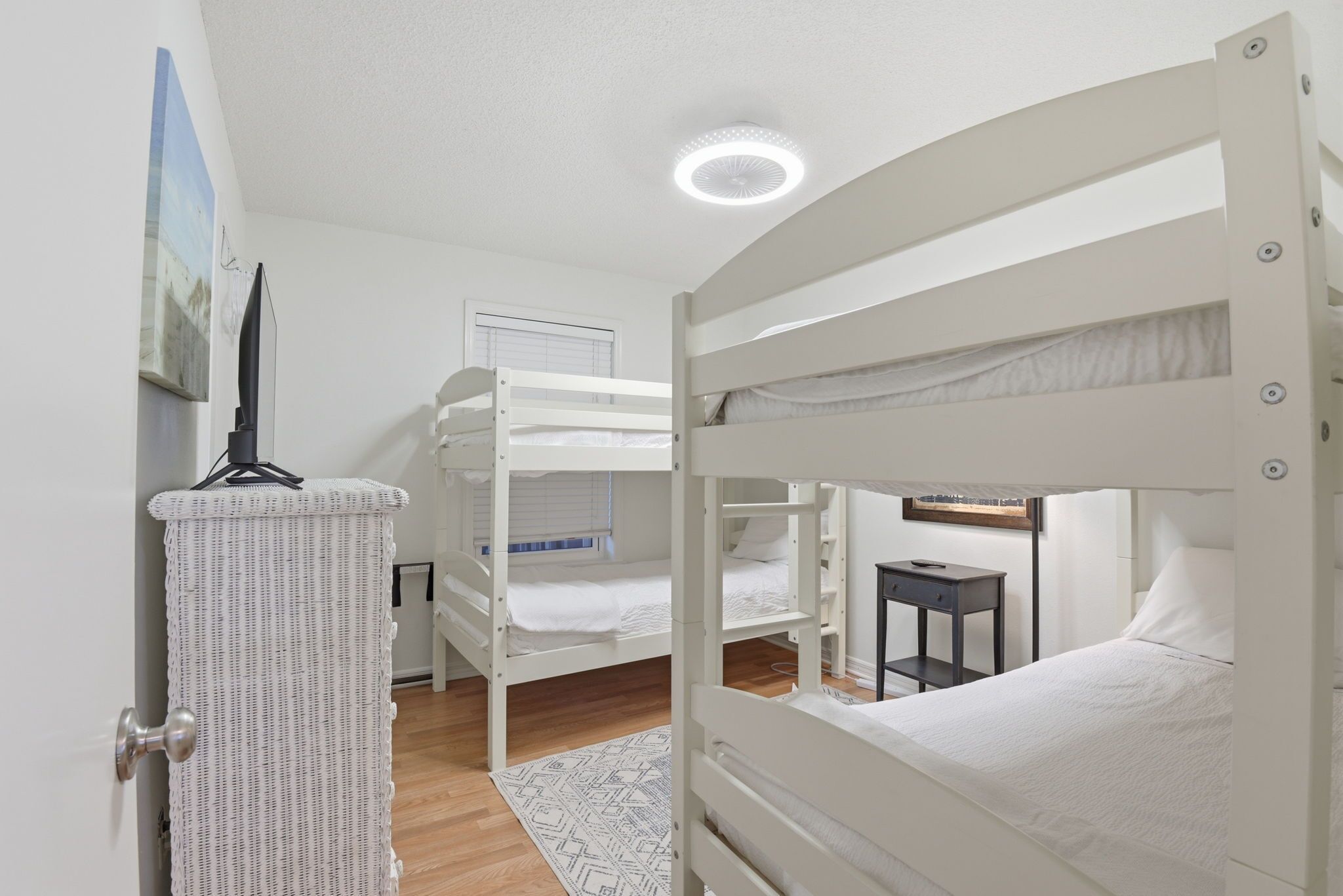 A room with bunk beds, a white door, a small table, and a ceiling light.