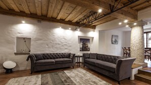 Een moderne woonkamer met twee grijze banken, een kamerkleed met een patroon en een stenen zuil.