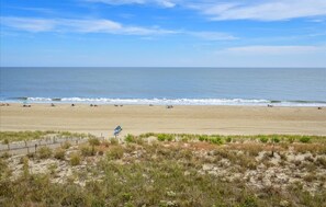 A beach with a fence and sparse vegetation in the foreground.