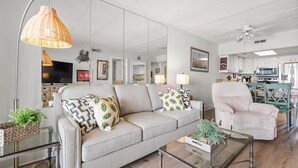 Ein Wohnzimmer mit einer Couch, Sesseln, einem Couchtisch und einem Fernseher.