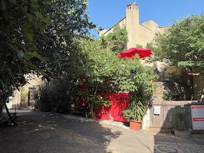 A courtyard with a red gate, a bench, and a potted plant.