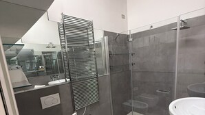 Ein modernes Badezimmer mit Duschkabine aus Glas, einem Bidet, einem Waschbecken und einem Spiegel.