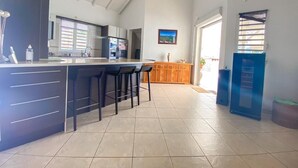 A spacious kitchen with a large island, bar stools, and a refrigerator.