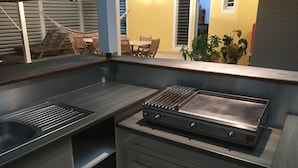 A compact kitchen with a stainless steel grill, a sink, and a small storage cabinet.