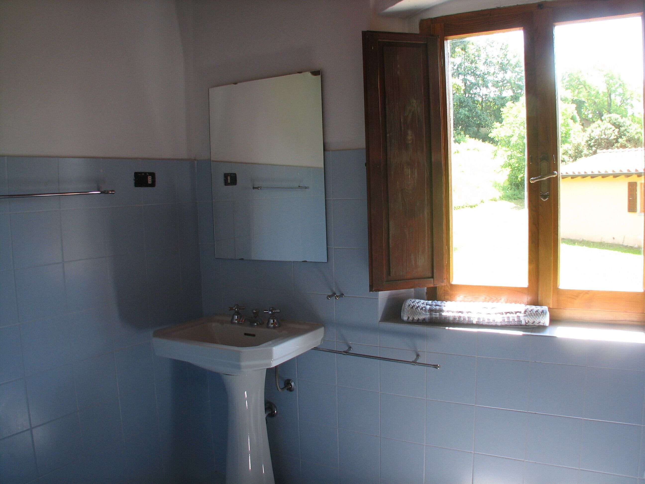 Une salle de bain avec un lavabo, un miroir et une fenêtre.