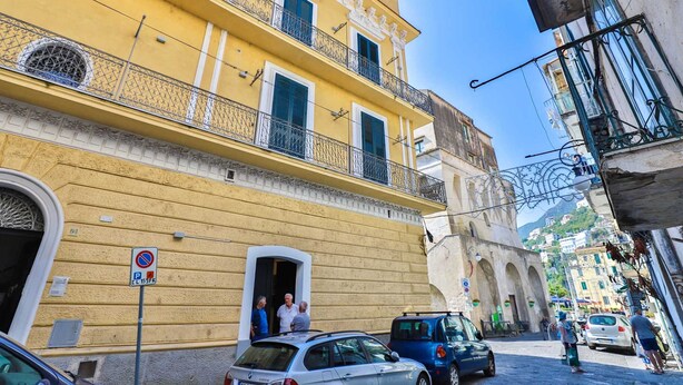A yellow building with a balcony, a no parking sign, and a car parked in front. - Della Monica Rooms (Vietri sul Mare)