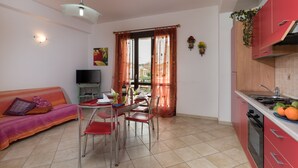 A compact living space with a dining area, kitchenette, and a sofa. - I tre Golfi Nespolo (San Vito Lo Capo)
