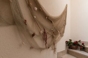 Uma rede bege pendurada em uma parede texturizada, decorada com conchas e algas secas.