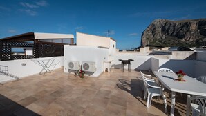A rooftop terrace with a white table and chairs, air conditioning units, and a view of a mountain. - I tre Golfi Nespolo (San Vito Lo Capo)