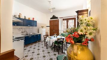 Una cocina con armarios azules, una mesa de comedor para cuatro personas y un florero con flores sobre la mesa.