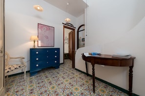 Traditional design features a patterned tile floor, a dresser, and a wooden table with papers.