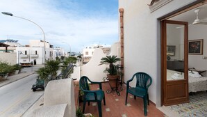 Een balkon met twee stoelen, een bloempot en uitzicht op de straat.