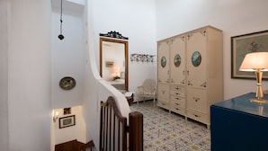 Een trap die leidt naar een slaapkamer met een grote garderobe, een klein tafeltje en een lamp.