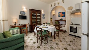Een eetgedeelte met een ronde tafel, stoelen en een televisie aan de muur.